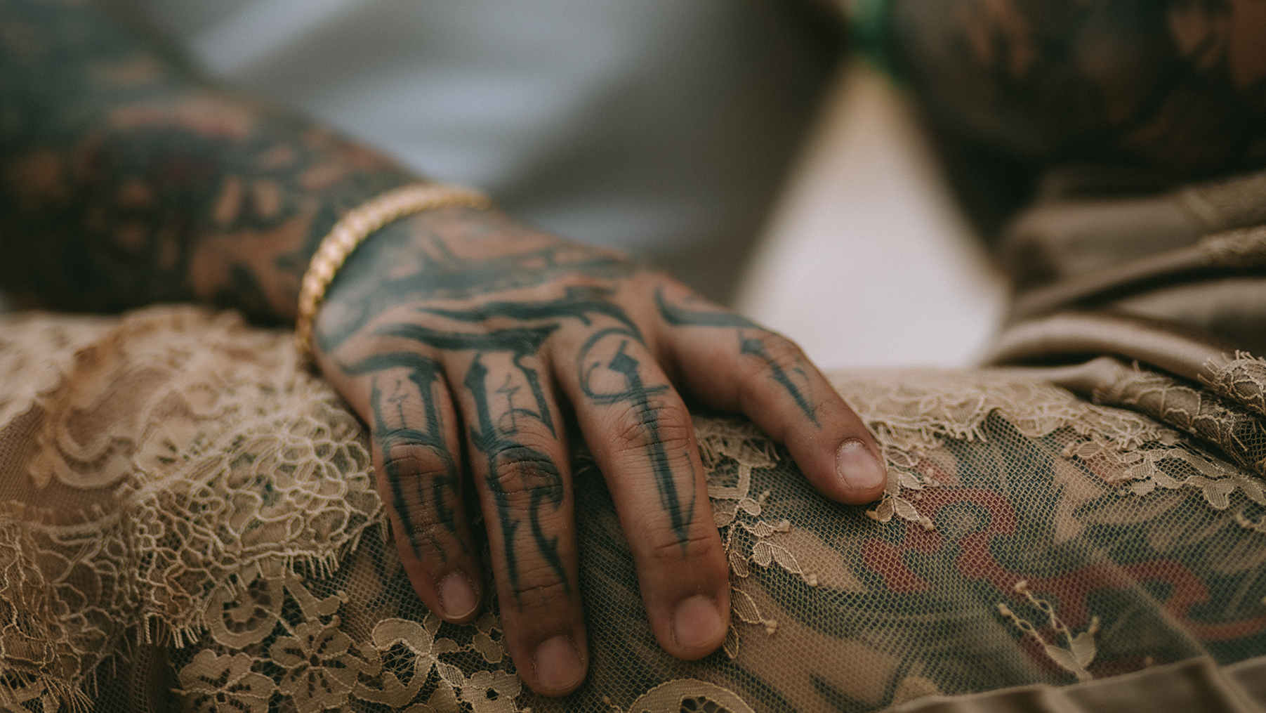 Two people with tattoos holding hands, blurred background